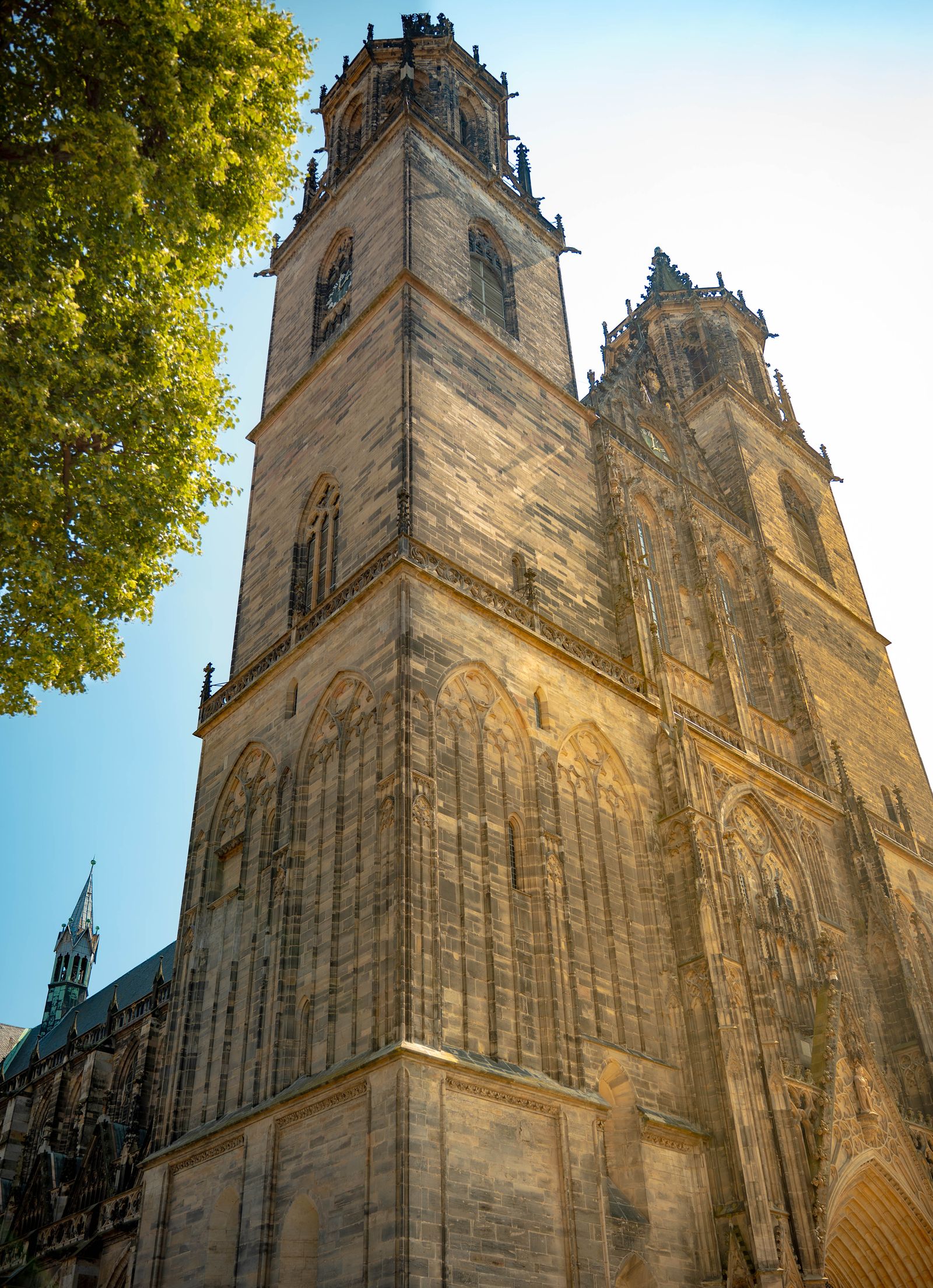 Gotischer Dom mit zwei Türmen in warmem Sonnenlicht, von unten fotografiert